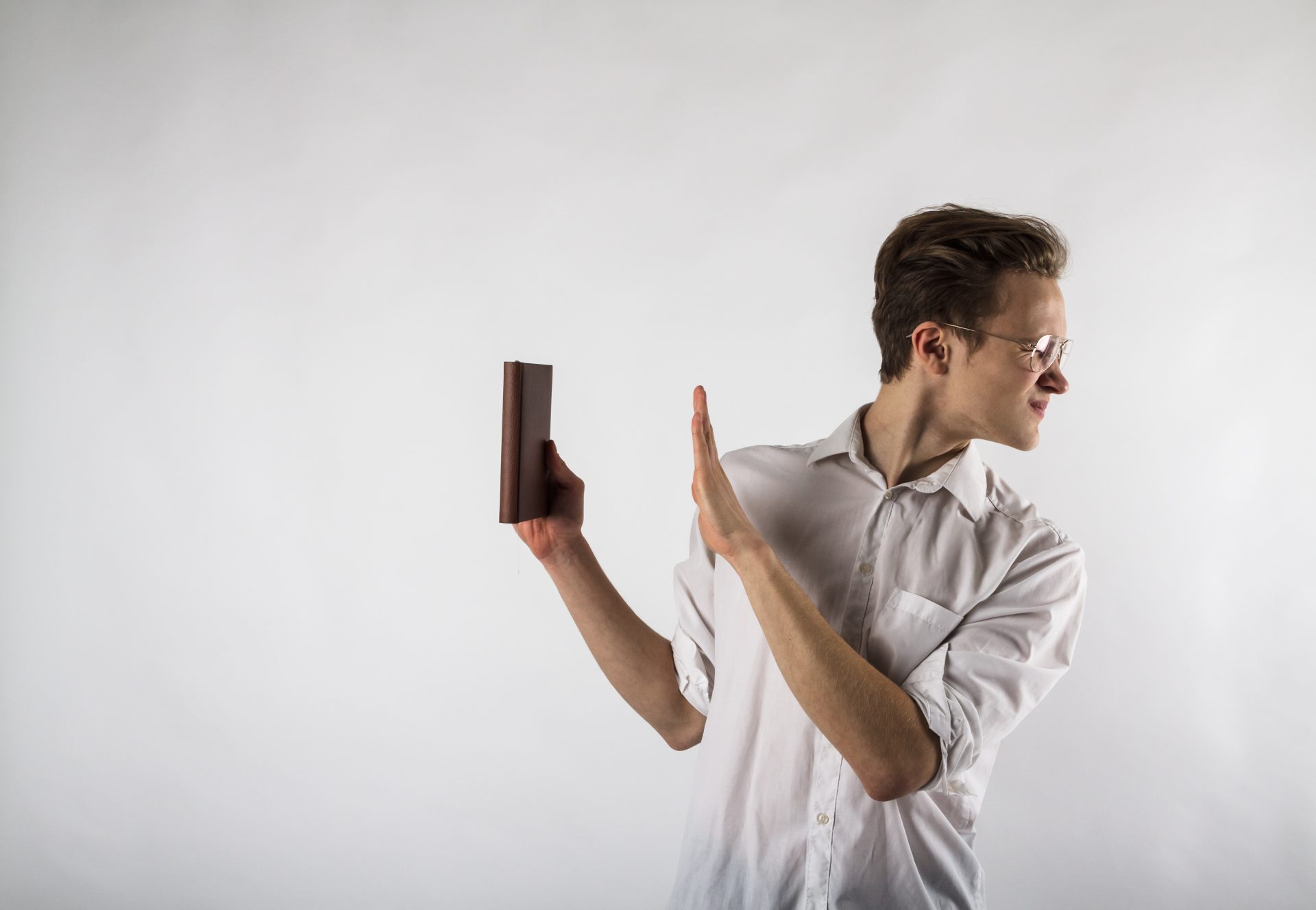 Young man holding workbook in his hands. Dislike and refuse conc
